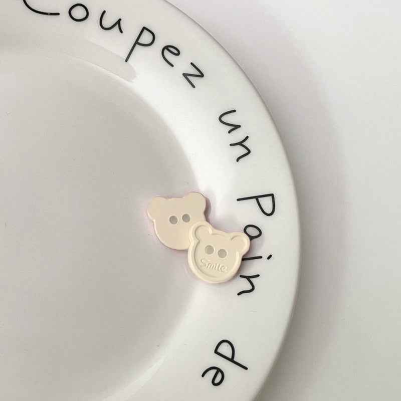 Light cream teddy bear face plastic buttons, each with two holes and “Smile” detail