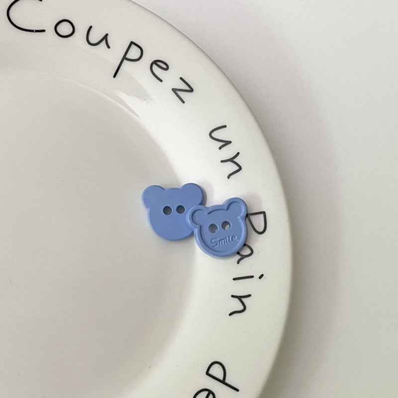Light blue cartoon teddy bear face plastic buttons, each with two holes and “Smile”