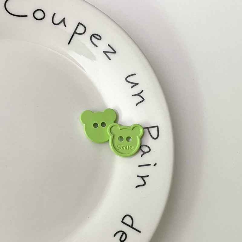 Green cartoon teddy bear face plastic buttons, each with two holes and “Smile”