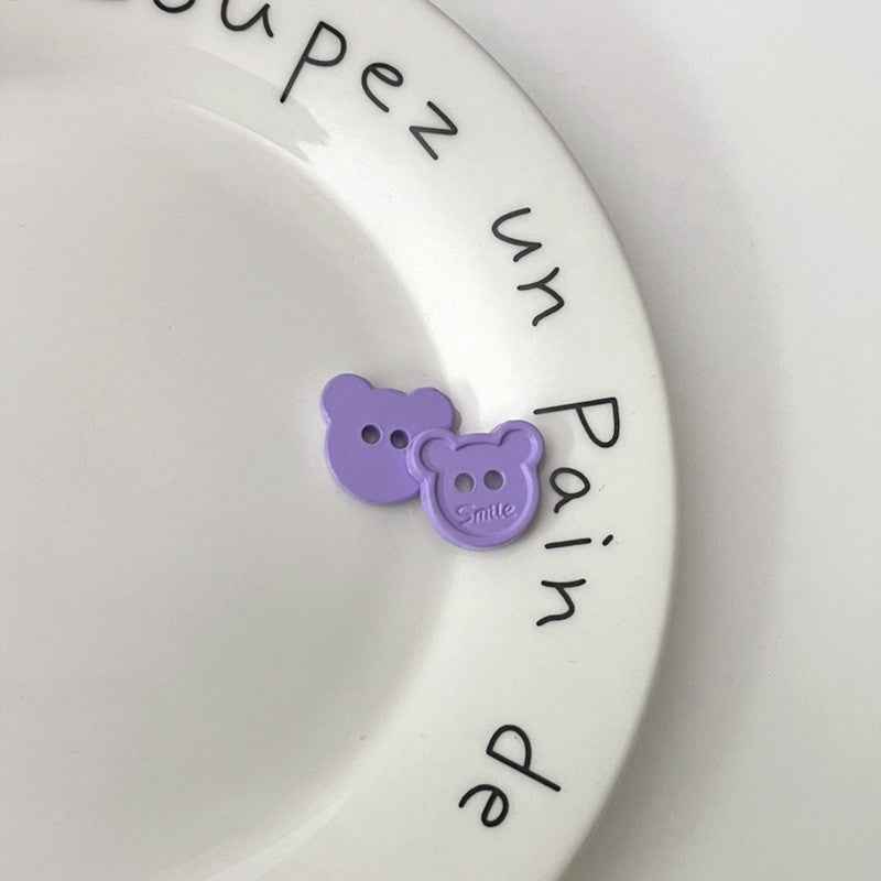 Purple cartoon teddy bear face plastic buttons, each with two holes and “Smile”