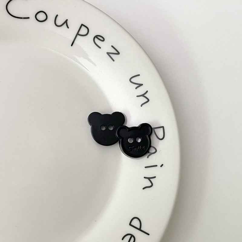 Black cartoon teddy bear face plastic buttons, each with two holes and “Smile”
