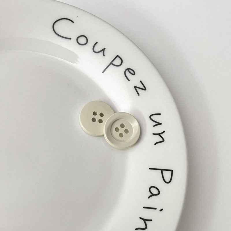 Two four-hole circular plastic buttons in white for children’s clothing