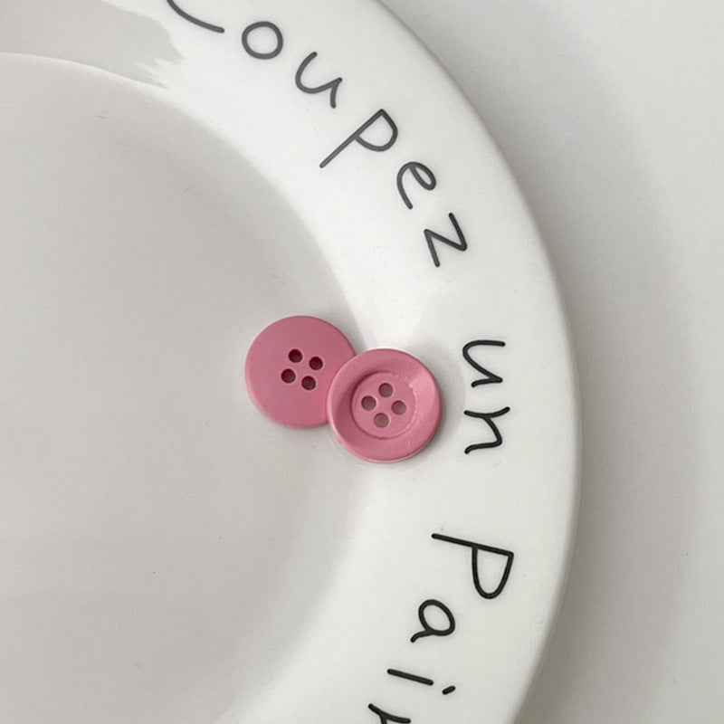 Two four-hole circular plastic buttons in pink for children’s clothing