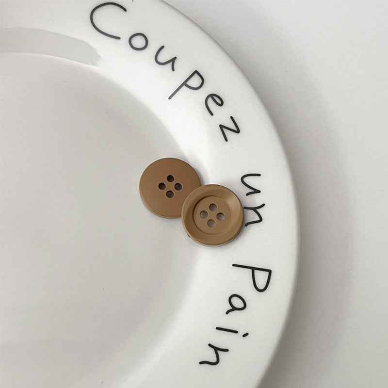 Two four-hole circular plastic buttons in tan and brown for children’s clothing