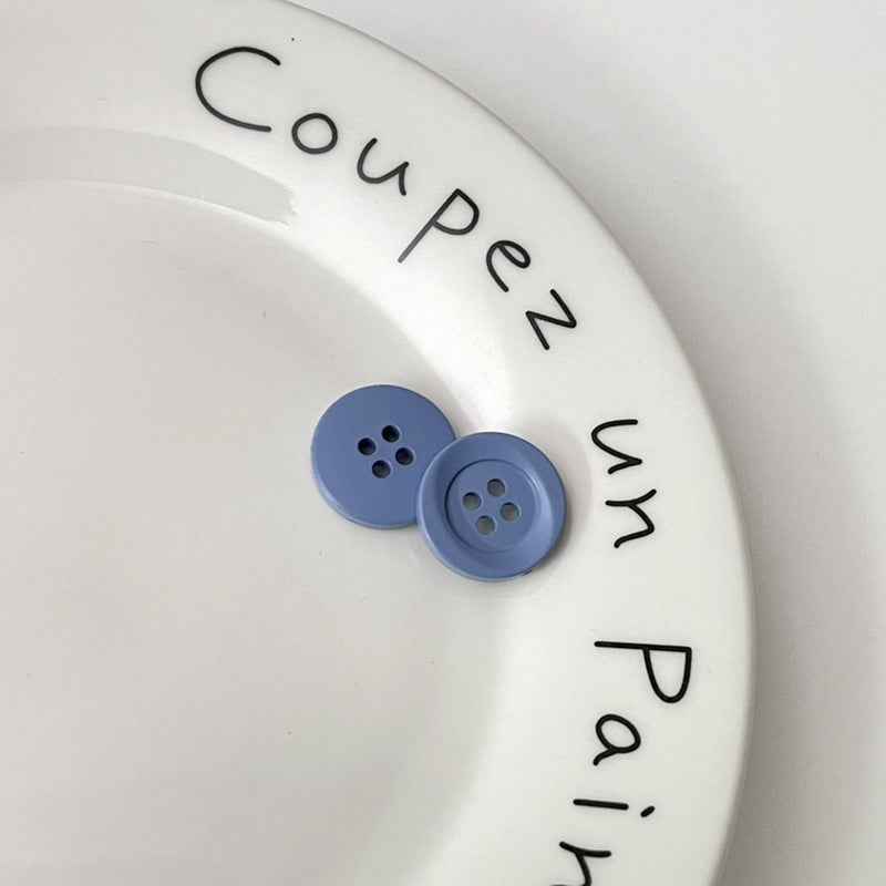 Two four-hole circular plastic buttons in light blue for children’s clothing