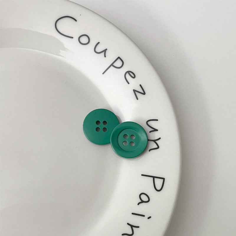 Two four-hole circular plastic buttons in green for children’s clothing