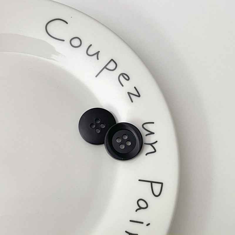 Two four-hole circular plastic buttons in black for children’s clothing