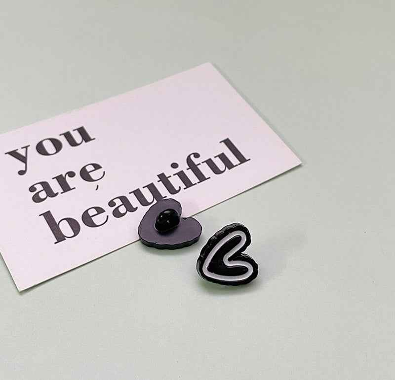 Black double-heart plastic button with glossy center and white-edged heart outline.