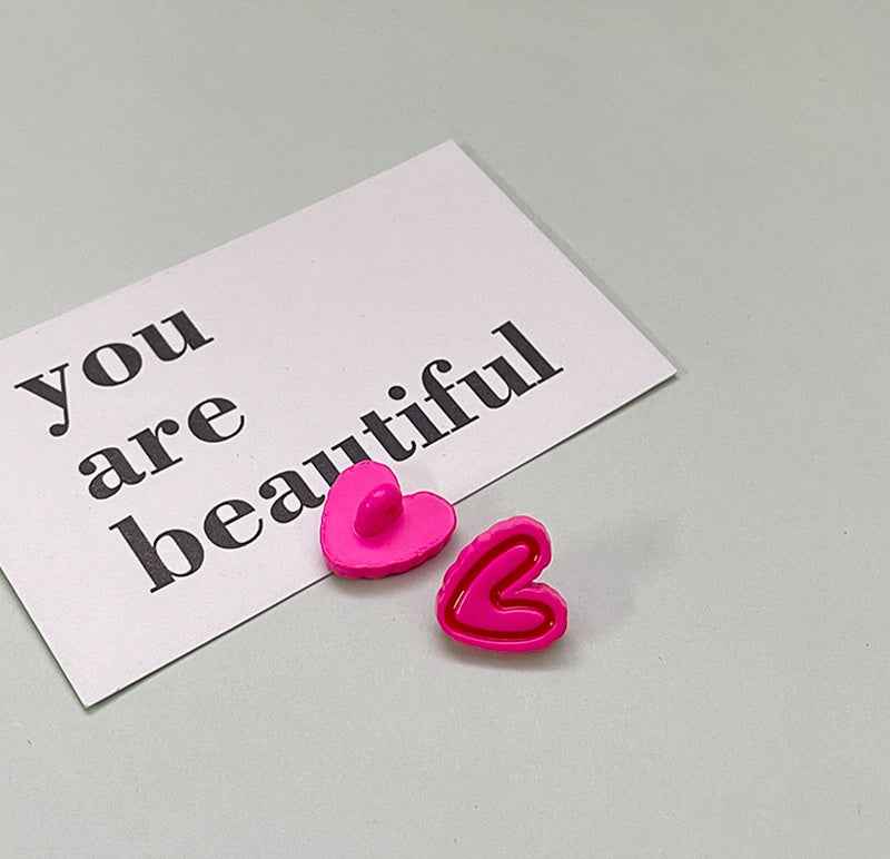 Bright pink double-heart plastic button pair with matching glossy heart outline.