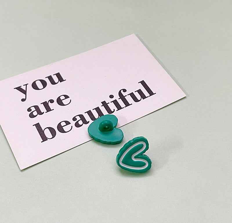 Green double-heart plastic button with rounded flat back and small center shank.