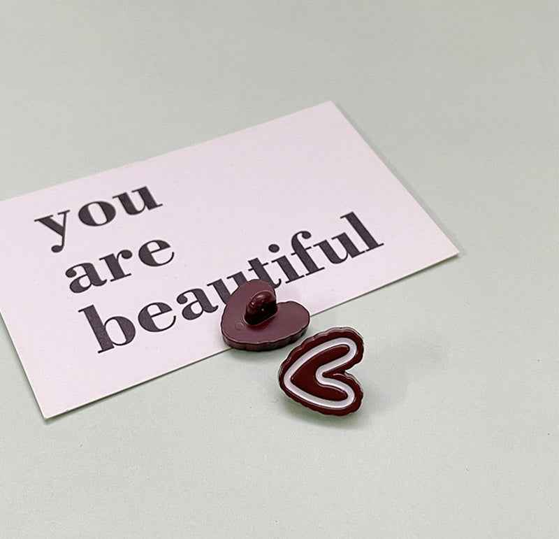 Dark maroon double-heart plastic button with small pearl center and red outline heart.