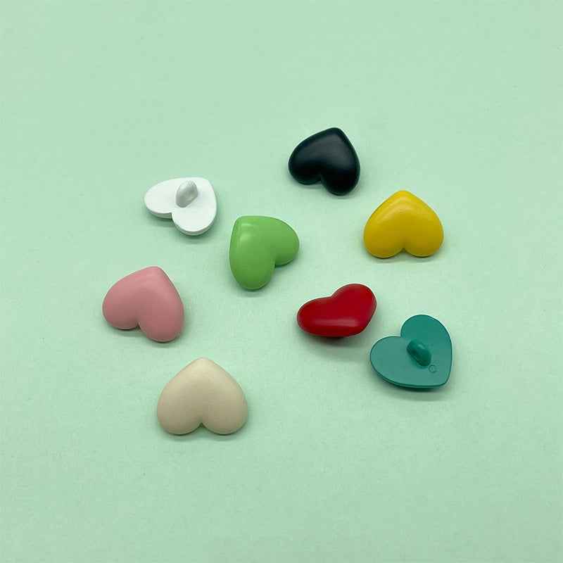 Assorted heart-shaped plastic shank buttons in red, black, yellow, green, pink, teal, cream