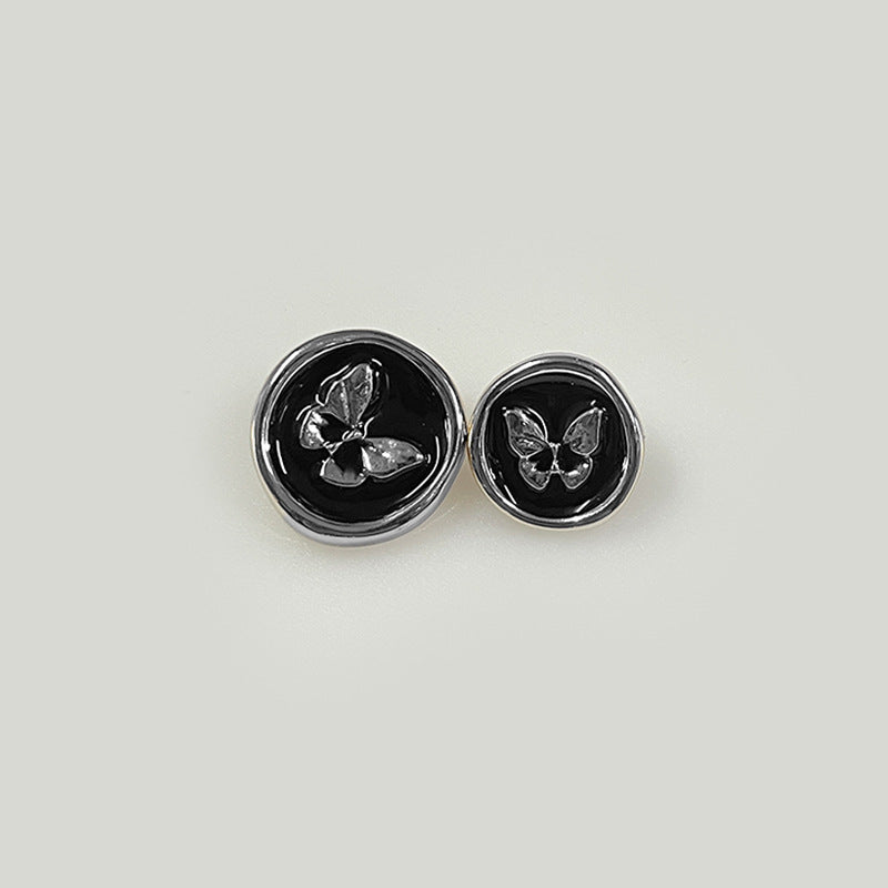 Pair of round black plastic shank buttons with butterfly emblem, shiny metal rim