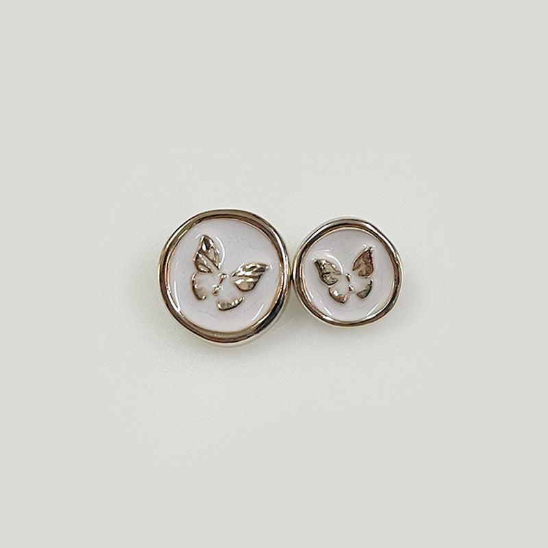 Pair of round white plastic shank buttons with butterfly emblem, shiny metal rim