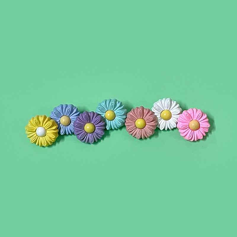Reihe bunter Gänseblümchen-Kunststoffknöpfe: rosa, blau, lila, weiß und gelb