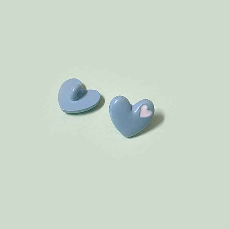 Light blue heart-shaped buttons with shanks and yellow inner-heart accent