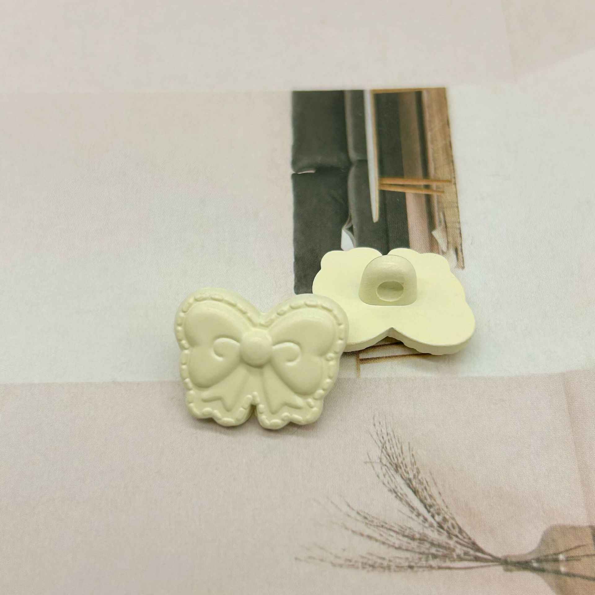 Cream butterfly-shaped shank buttons with bow detail, side-by-side