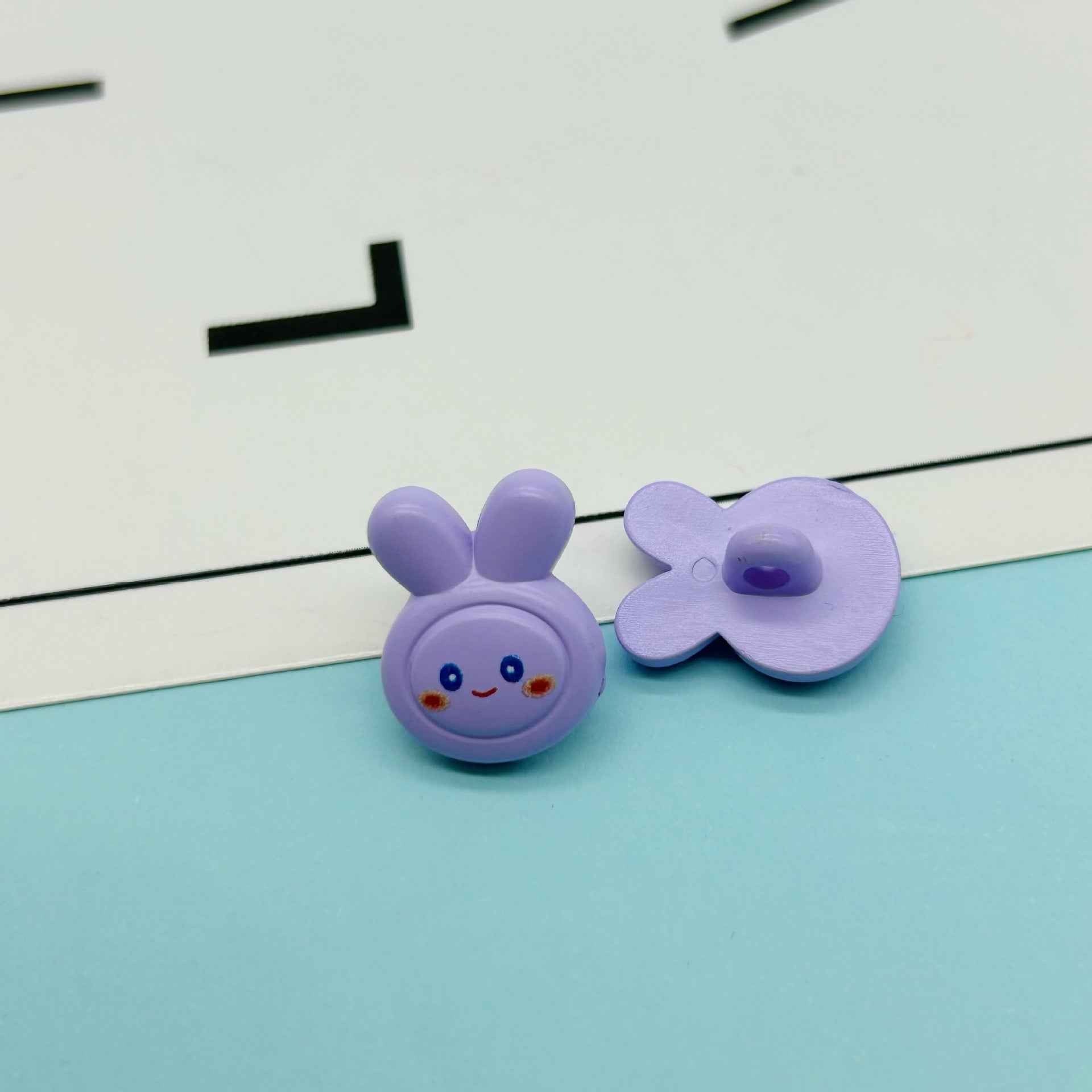 Purple cartoon rabbit buttons: bunny face with ears and purple flower-shaped bow