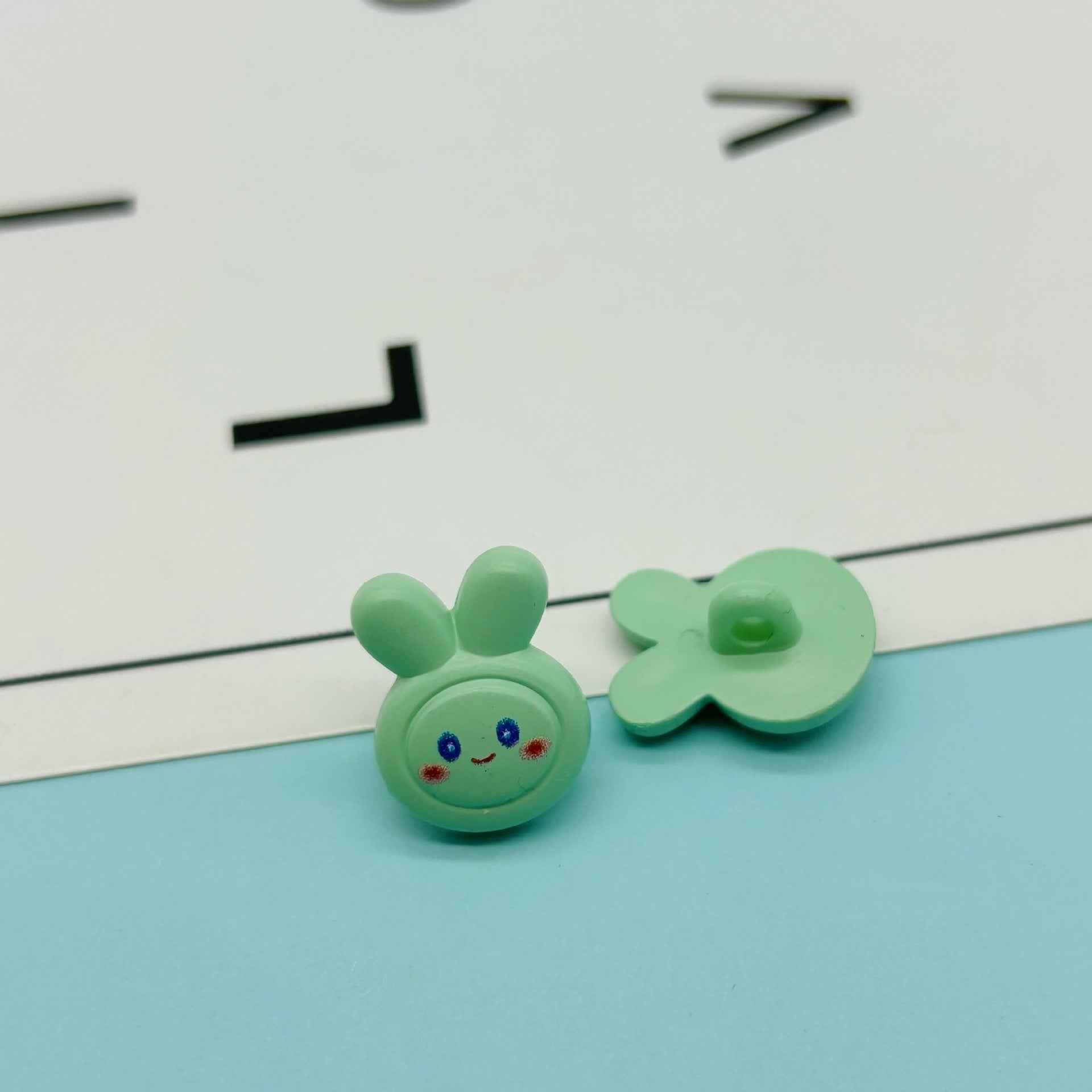 Green cartoon rabbit buttons: bunny face with ears and green flower-shaped bow button