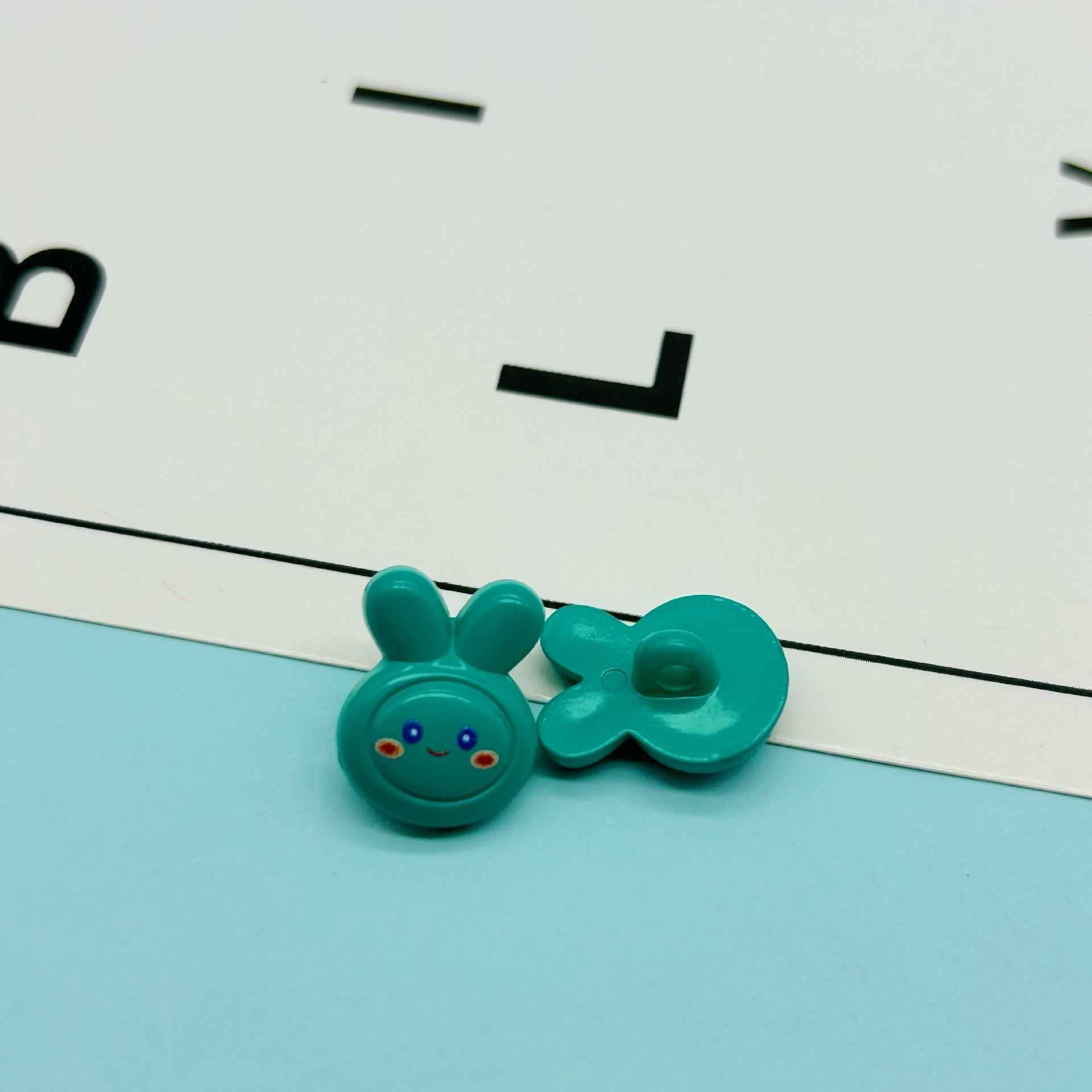 Teal cartoon rabbit buttons: bunny face with ears and matching bow-like button