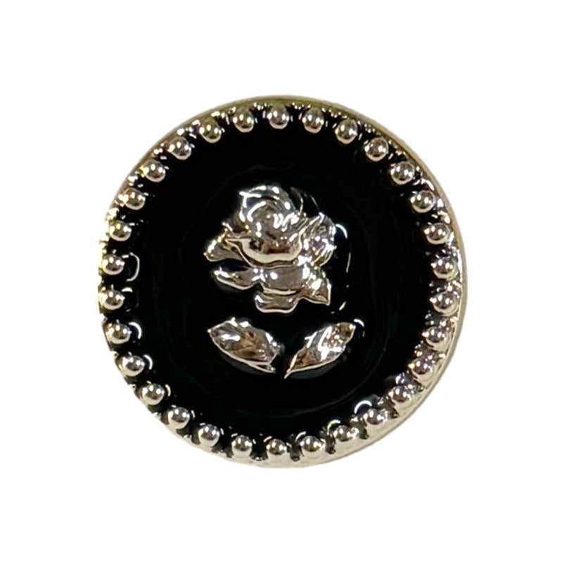 Round black plastic shank button, gear-edged border, rose pattern medallion