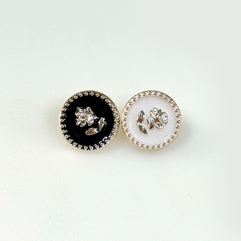 Pair of gear-edged rose plastic shank buttons: one black, one white with beaded rim