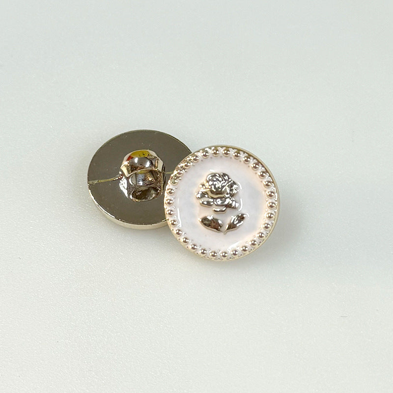 White plastic shank button with rose medallion and gear-edged beaded rim, back view