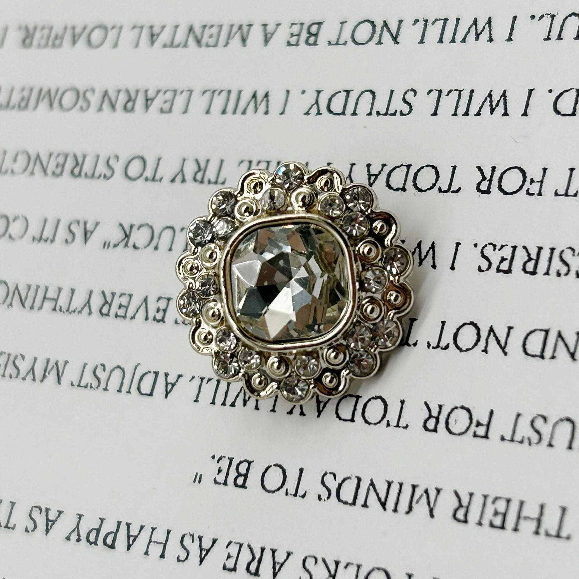 Gold-tone diamond-flower shank button, faceted centerpiece on ornate plastic setting.