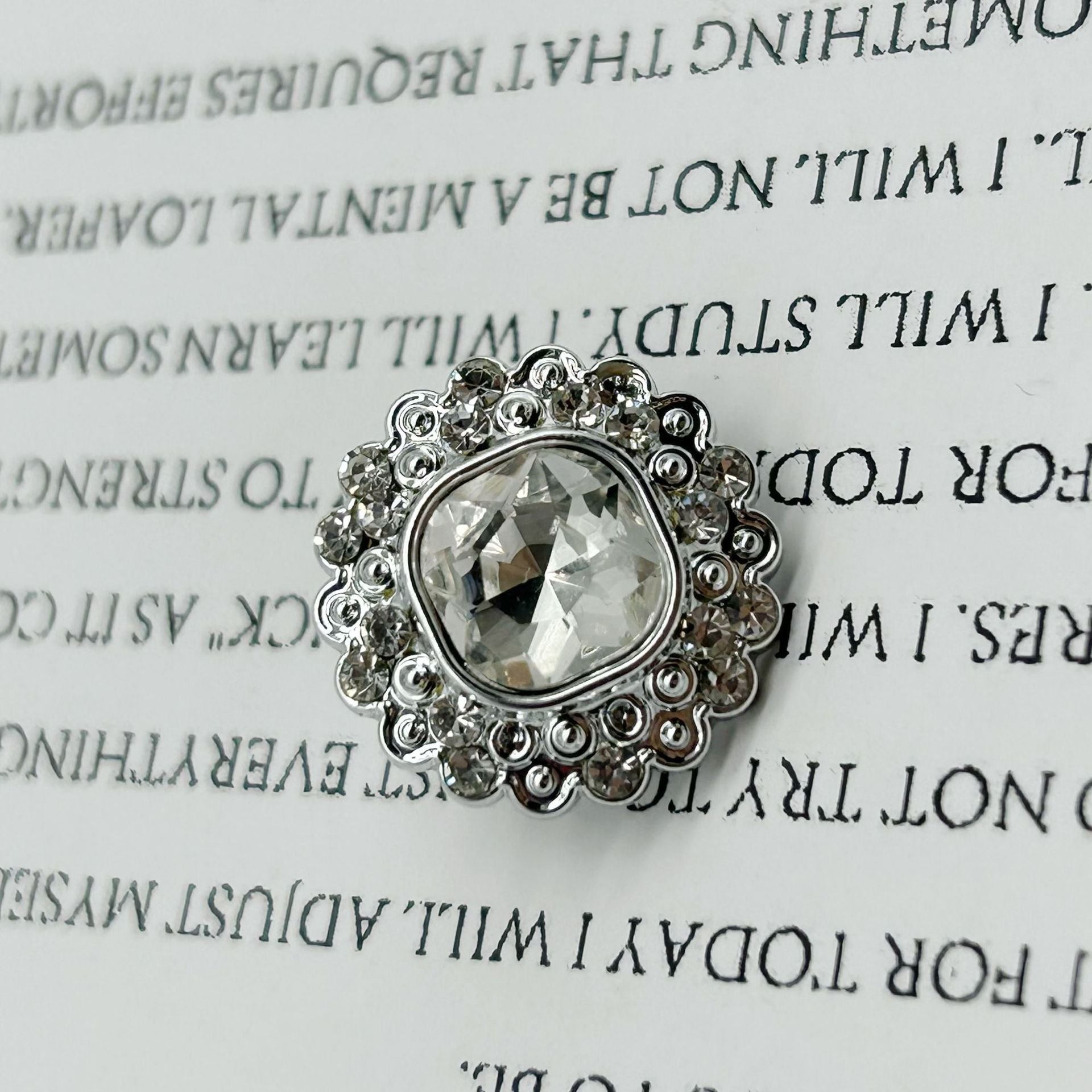 Silver-tone diamond-flower shank button, faceted square-center on ornate plastic.