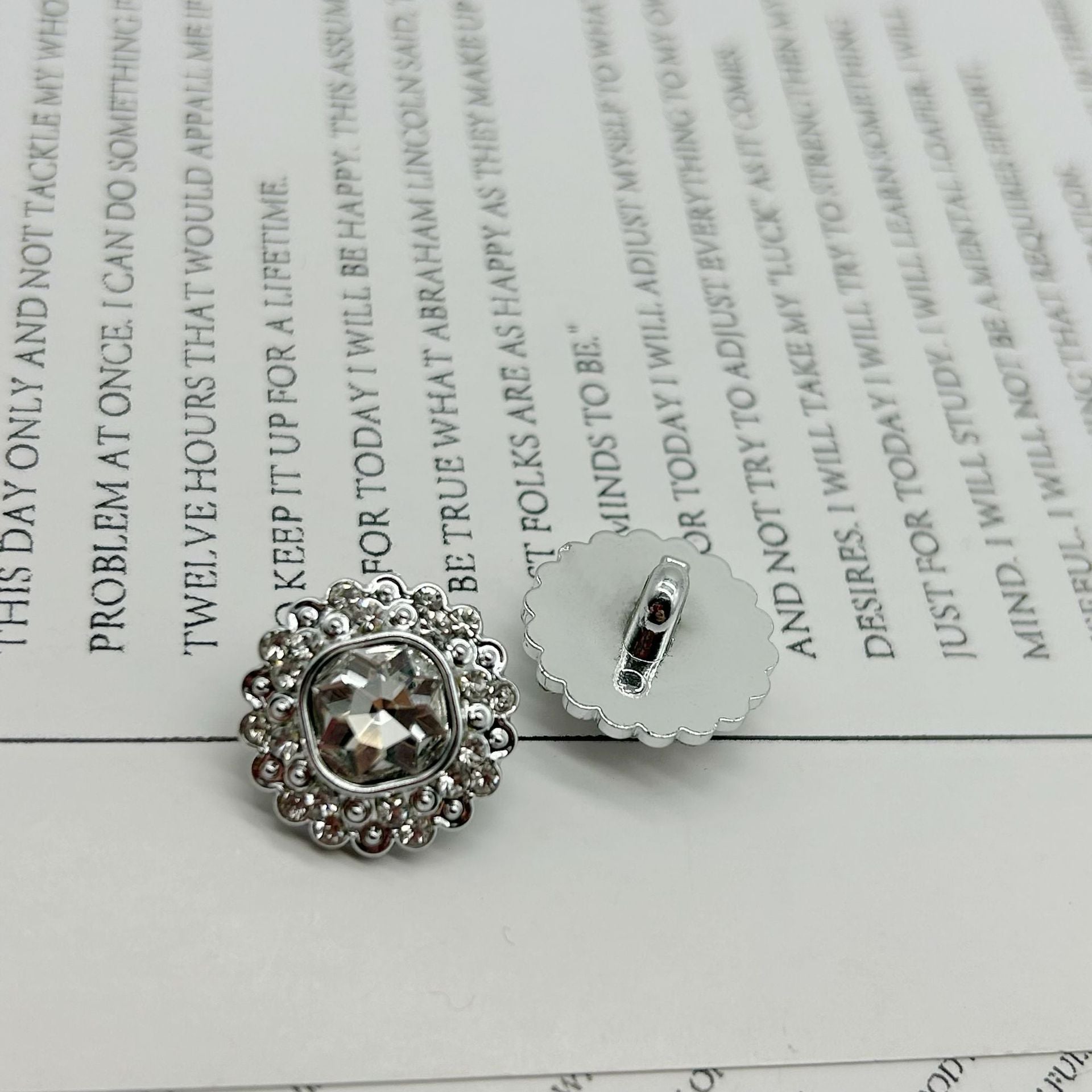 Diamond-flower shank button, silver-tone plastic with faceted center, 1 visible.