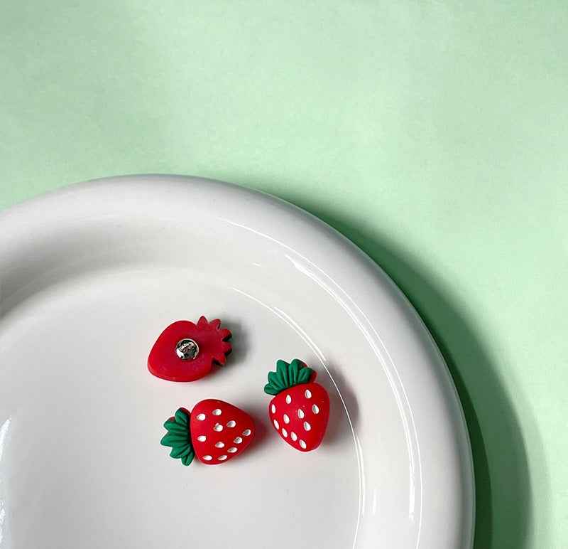 Red strawberry button set in dish, green leaves and white spots
