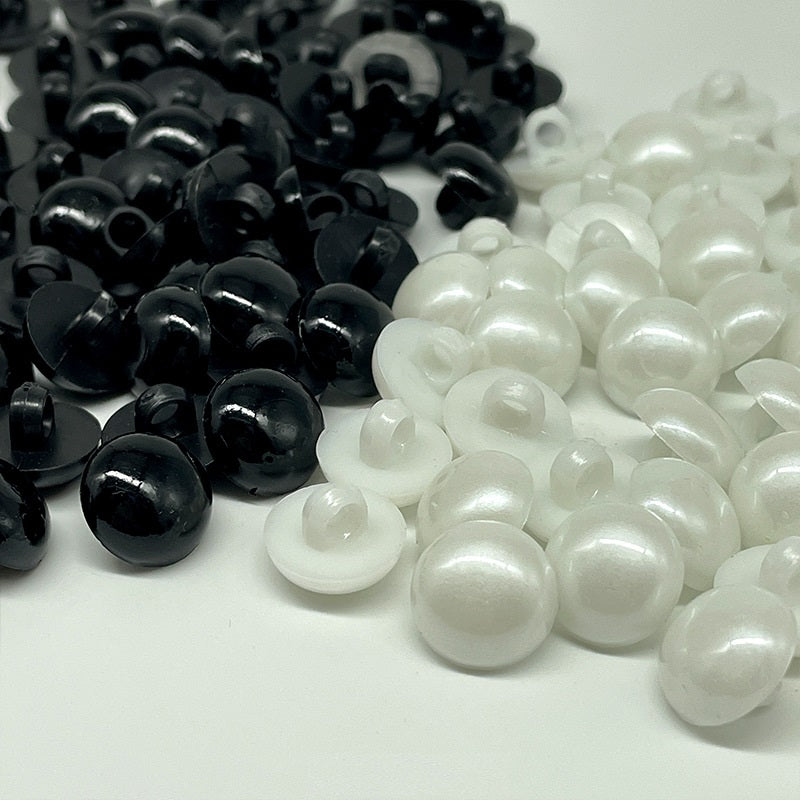 Mixed black and white plastic mushroom buttons, each with sew-on shanks