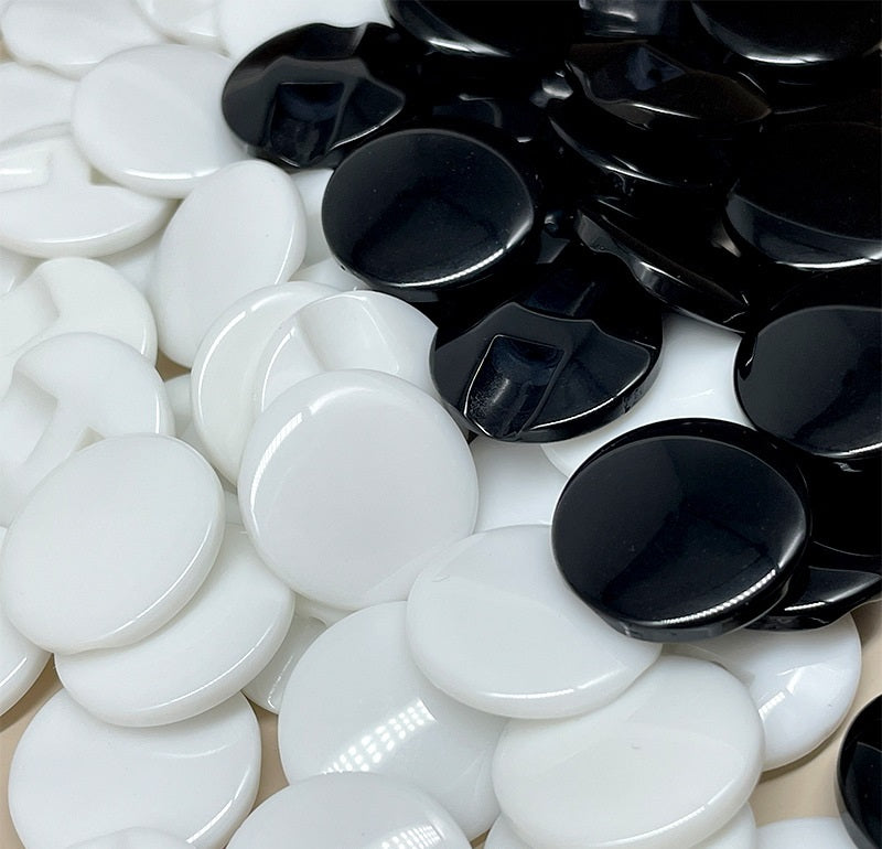 Black and white resin concealed-hole buttons, glossy round discs, close-up