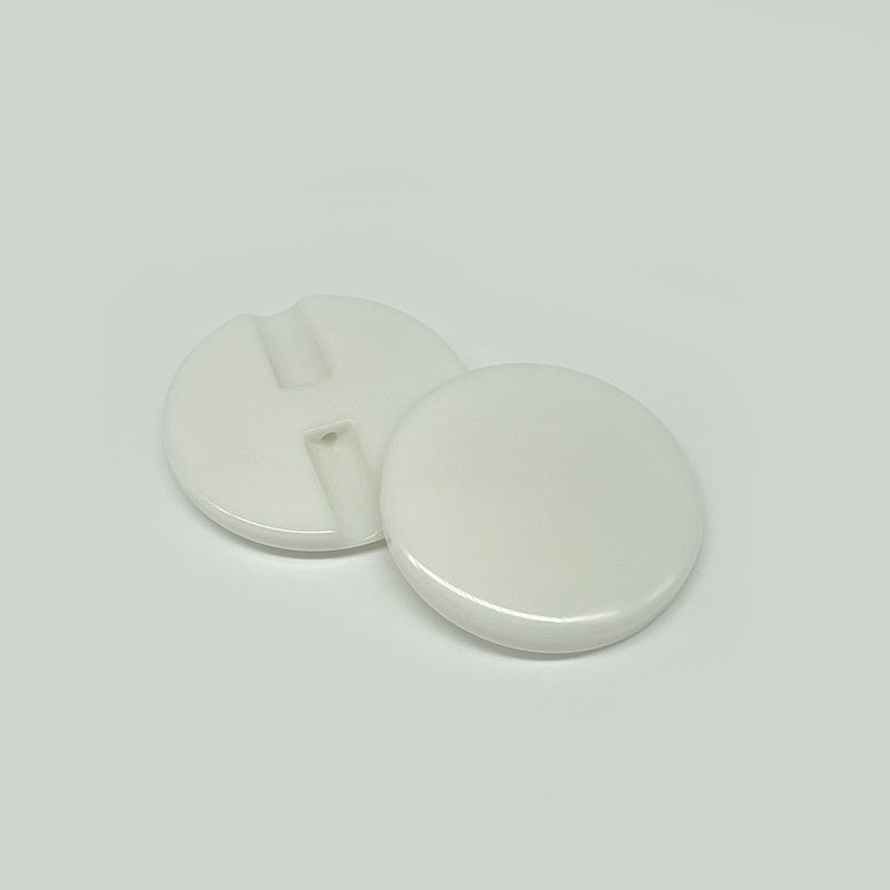 Two white resin concealed-hole buttons, flat backs with center slot
