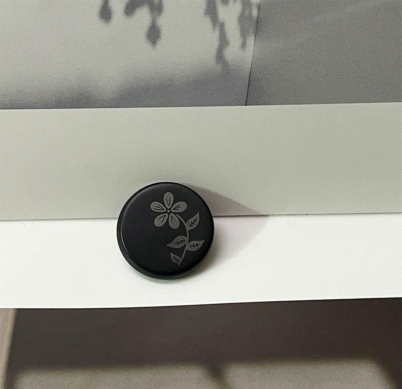 Black round resin button with floral laser-cut pattern and metal shank