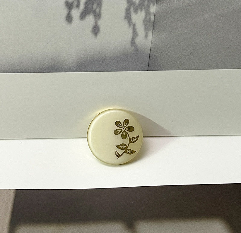 White round resin button with floral laser-cut flower and leaf pattern, metal shank