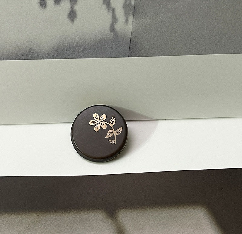Coffee-brown round resin button with laser-cut flower and leaf pattern, metal shank