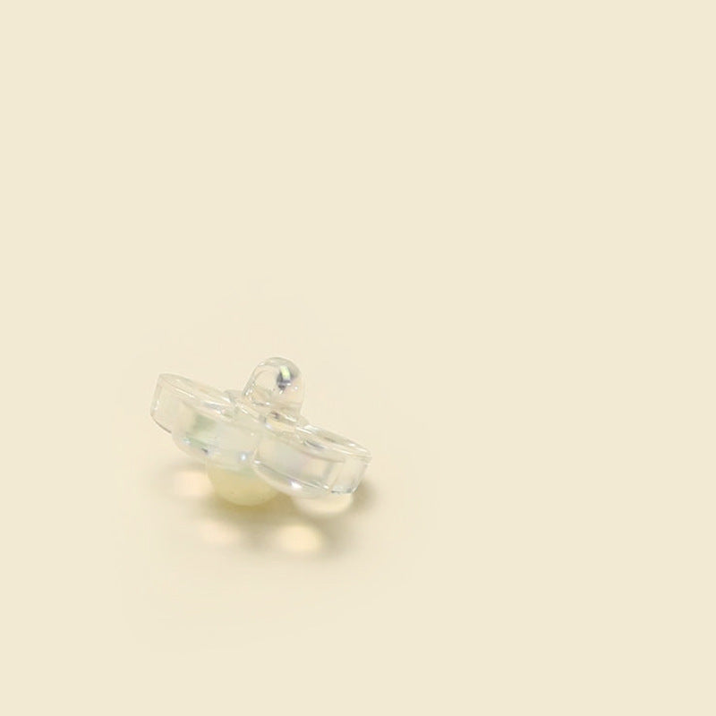 Clear resin flower button with shank, side view, glossy iridescent center