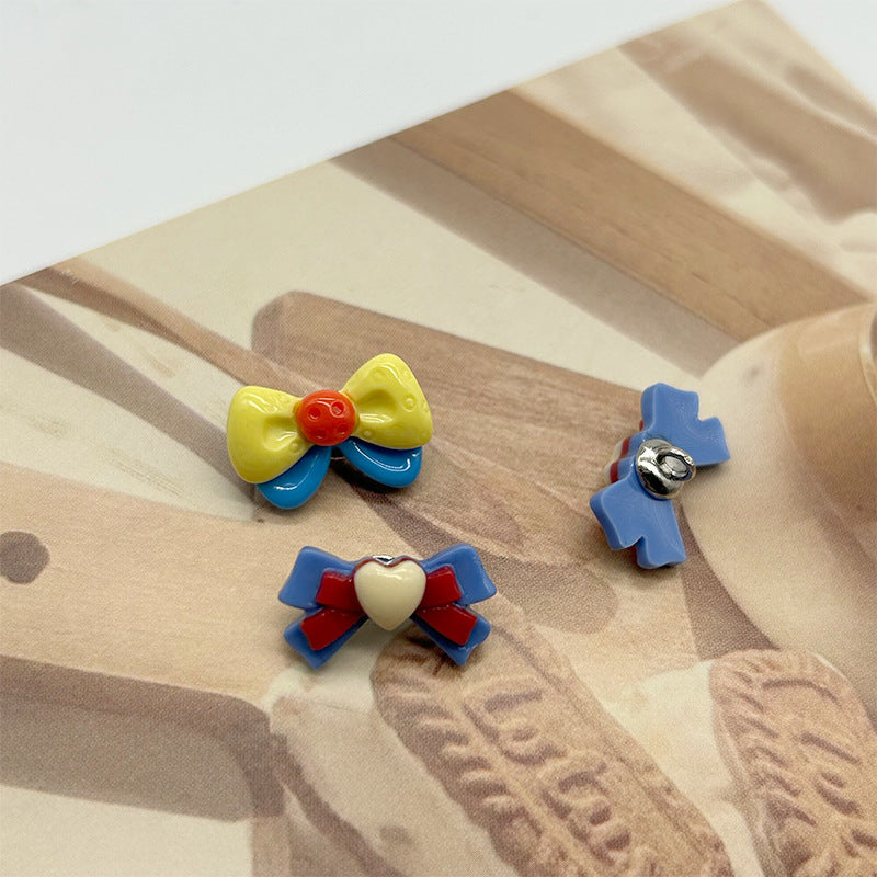 Cartoon bow resin buttons on fabric: yellow/blue and blue/red with metal shanks