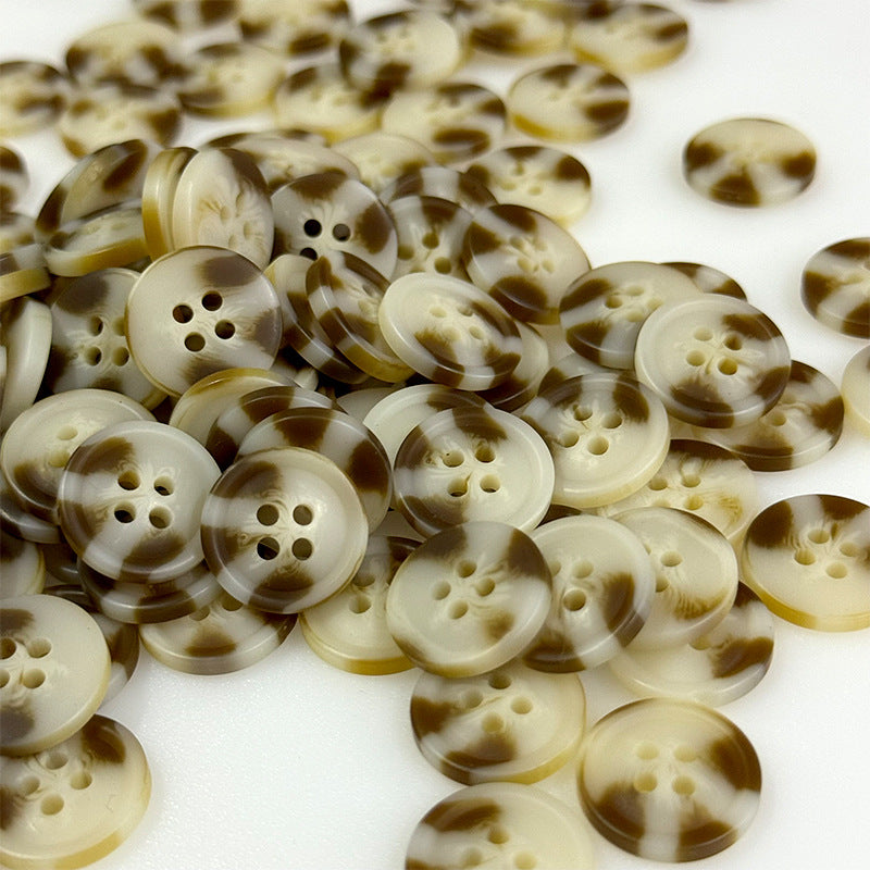 Mixed pile of round resin buttons in brown pattern, four-hole design.