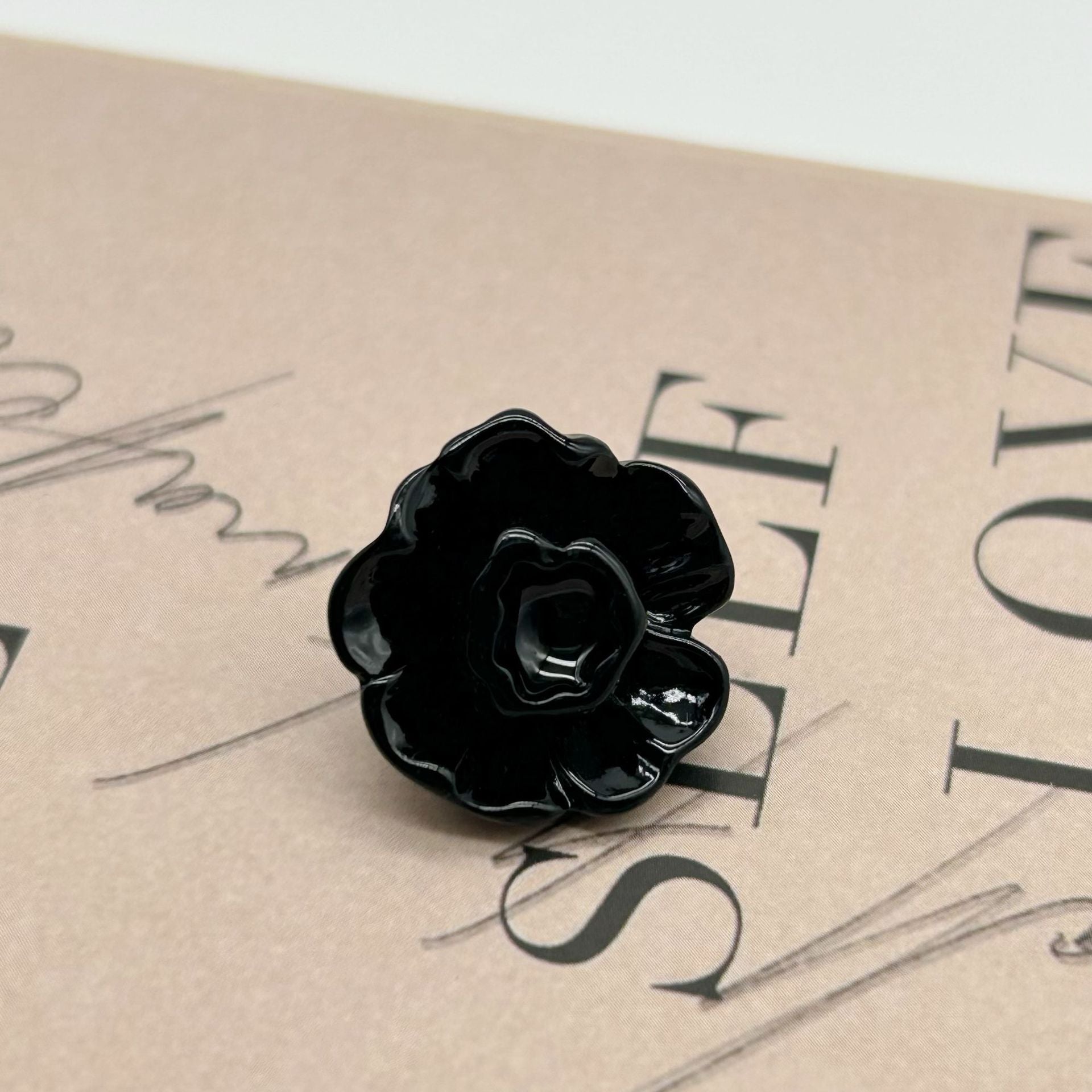 Black 3D flower button with metal shank, glossy petals and backing