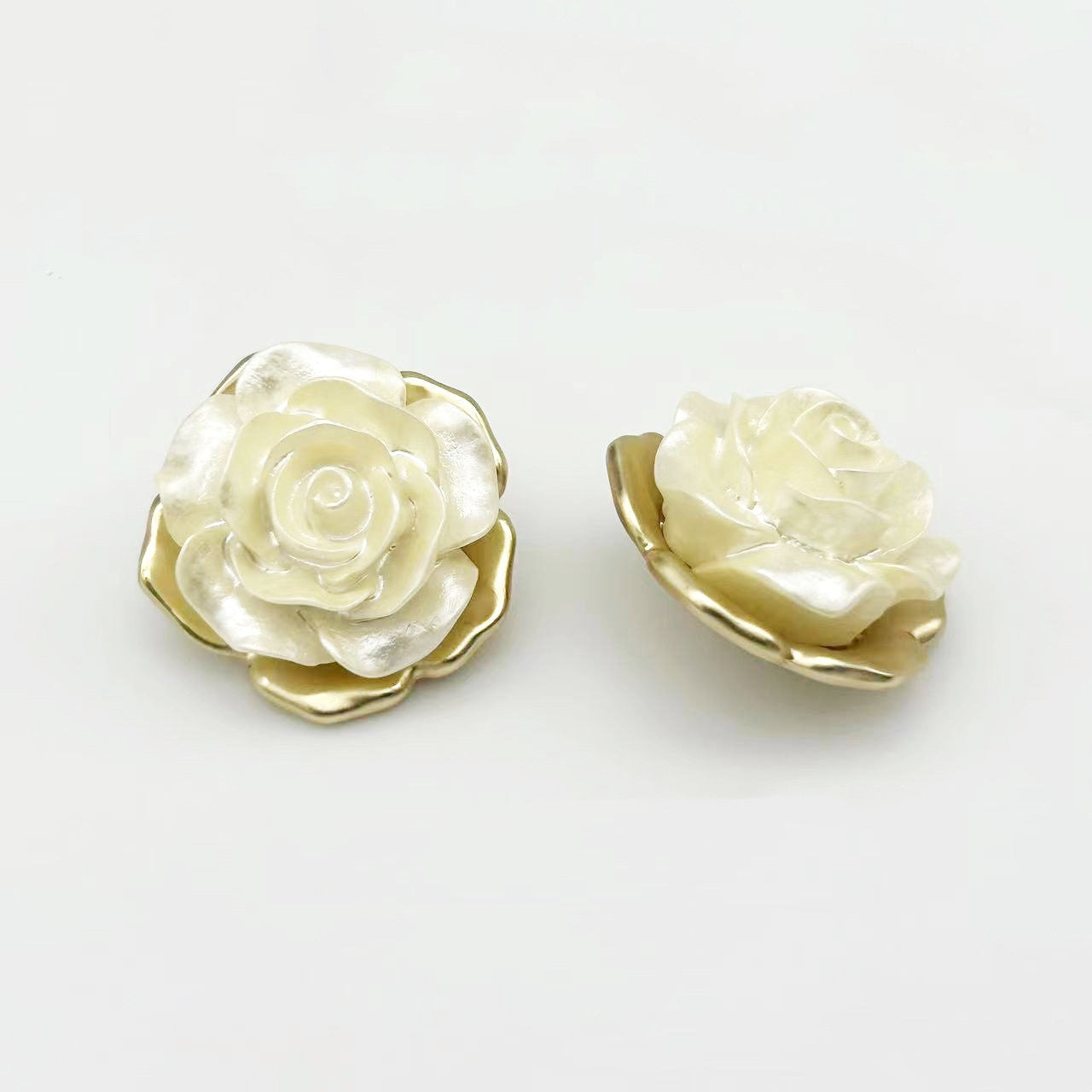 Two rose-shaped alloy buttons with shank, ivory petals and gold-tone border