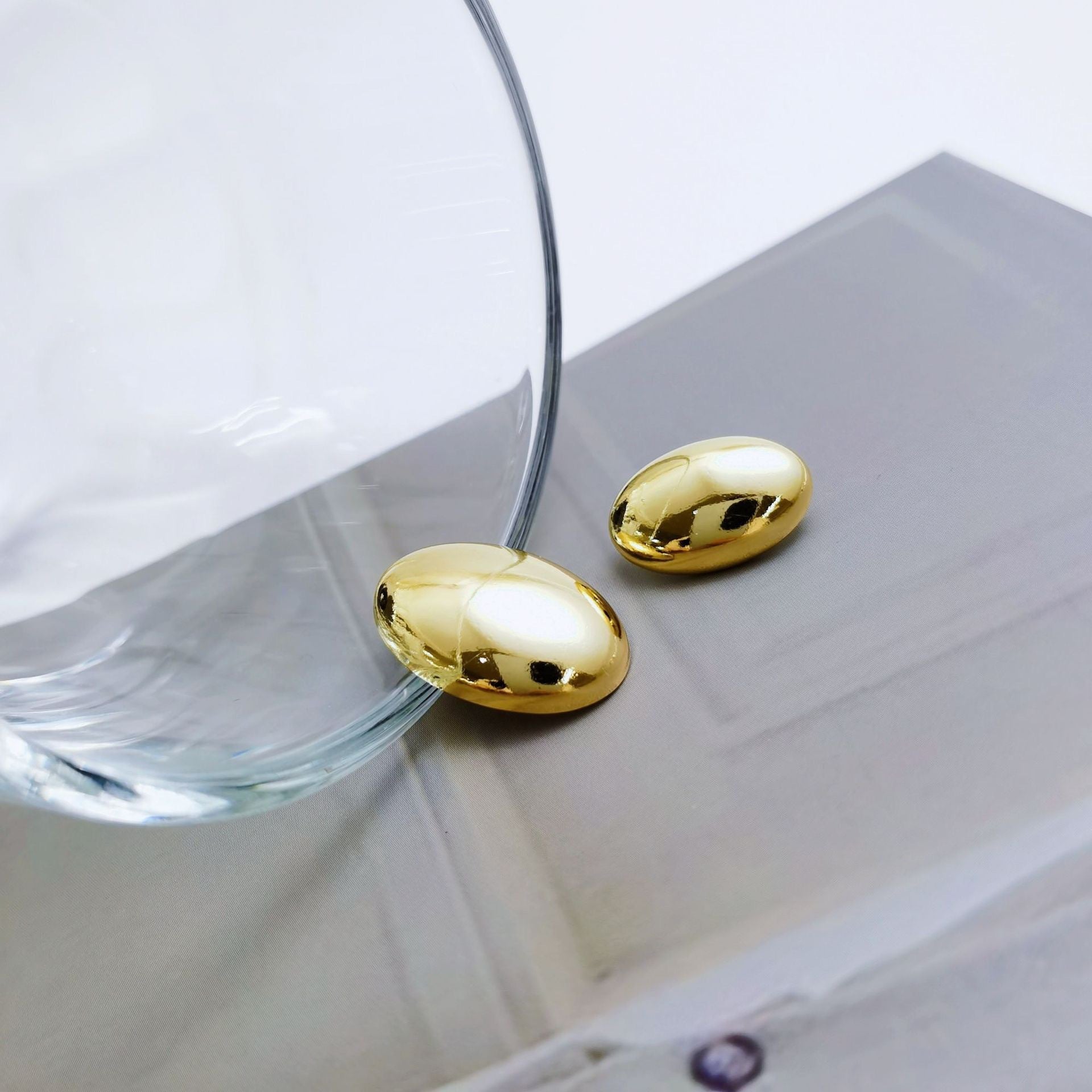 Light gold oval metal buttons with shanks, smooth glossy oval caps