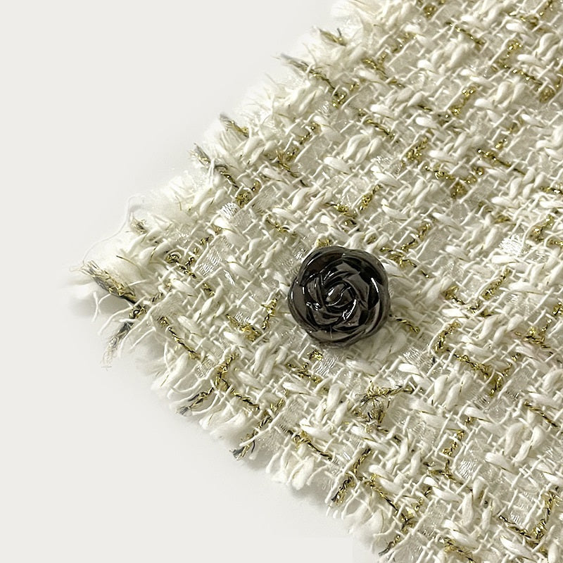 Bouton métal rose avec tige, noir pistolet, posé sur tissu texturé, vue rapprochée