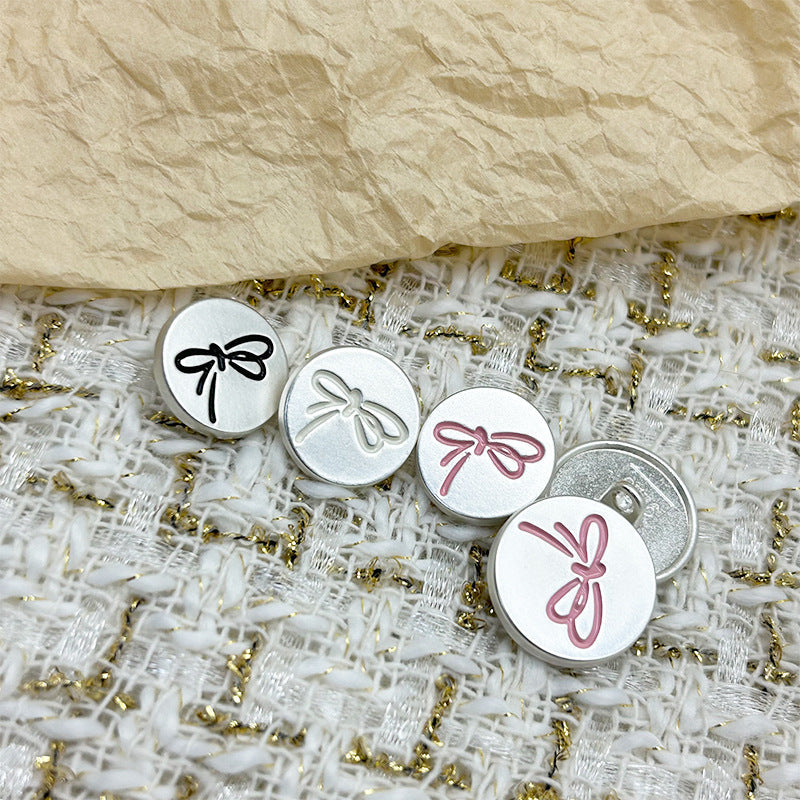 Round painted metal flat buttons with shanks: black, white, and pink bow patterns