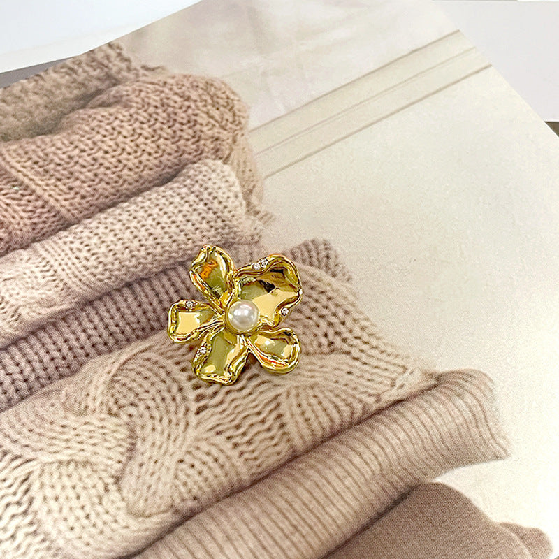 Gold flower-shaped metal sewing button with central pearl and small diamond-like inlays