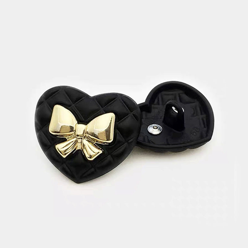 Black heart bow metal button with gold bow centerpiece; reverse side shown