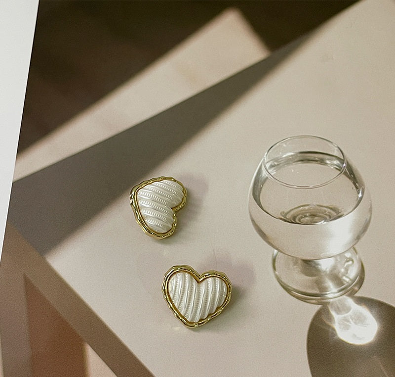 Two gold-and-white heart buttons with shanks, white ribbed center and gold edge