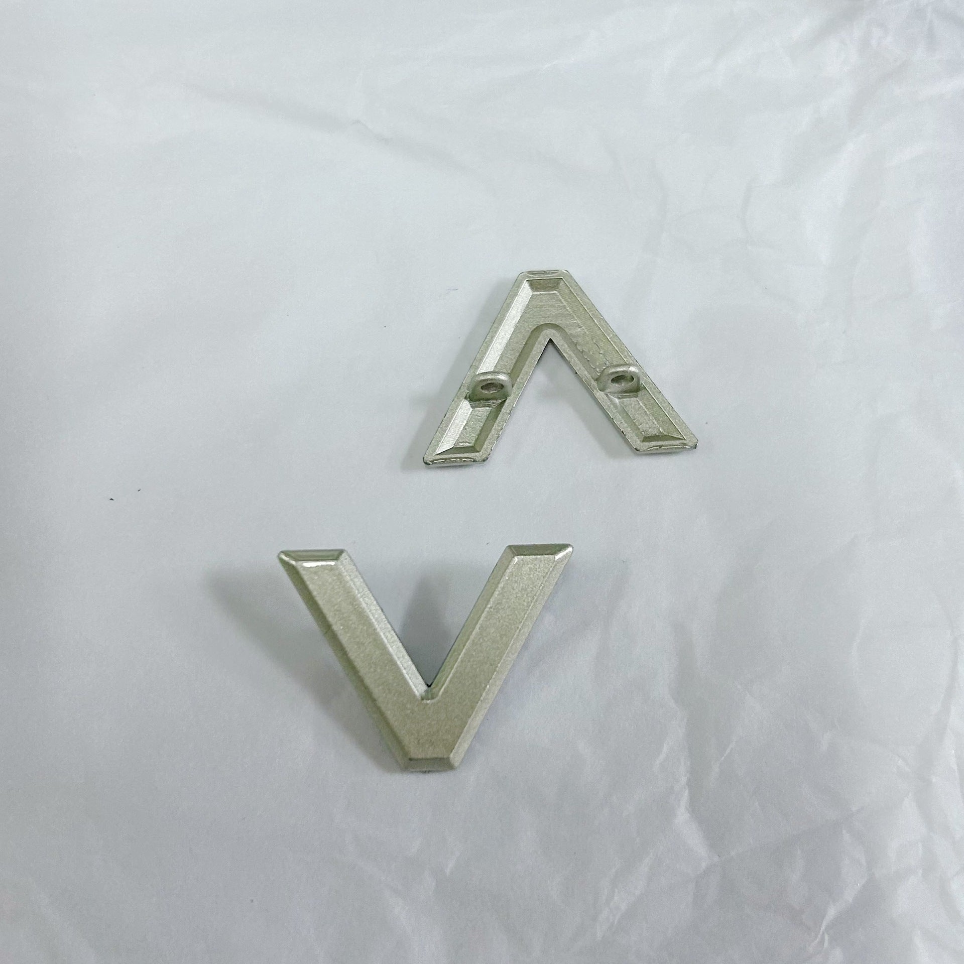 Silver V-shaped two-prong metal button with two short attachment prongs