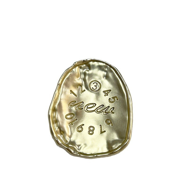 Gold oval metal button with embossed numbers around 12 and decorative script